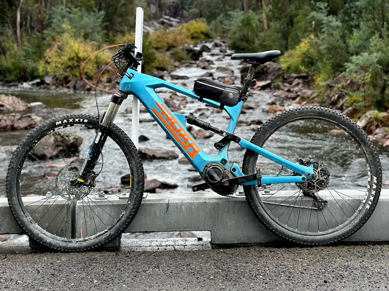 The turquoise Roar eBike beside a creek
